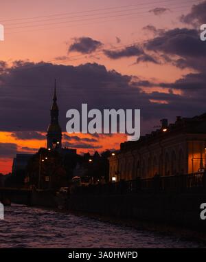 Une scène de coucher de soleil pittoresque avec une rivière, une silhouette de l'architecture baroque de Saint-Pétersbourg, et un ciel vibrant et coloré créant un calme Banque D'Images