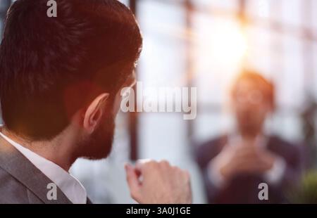 Un jeune homme s'assoit avec son dos à la caméra à une table dans un bureau. Banque D'Images