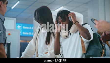 Point de contrôle de sécurité à l'aéroport : personnes multiethniques, voyageurs mettant des bagages, objets personnels dans des plateaux en plastique pour le balayage par rayons X du détecteur de métaux. Responsable de la sécurité contrôlant les procédures de contrôle TSA. Banque D'Images