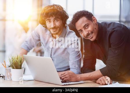 Professionnels d'affaires collaborant joyeusement dans un bureau moderne avec la technologie. Banque D'Images
