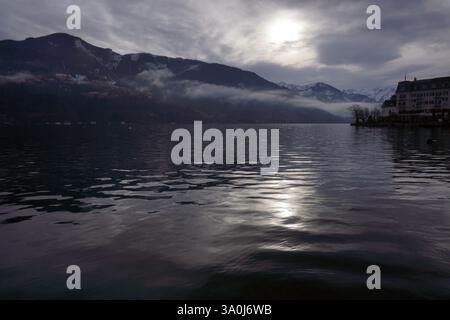 lac de montagne d'hiver, sommet de montagnes couvertes de neige, temps nuageux. Maisons près de l'eau Banque D'Images