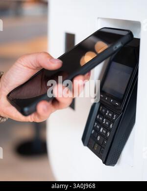 Le client effectue un paiement sans contact avec son smartphone au terminal NFC Banque D'Images