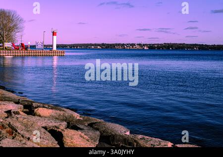 Rivage rocheux et entrée d'un port en début de soirée sous un ciel rose Banque D'Images
