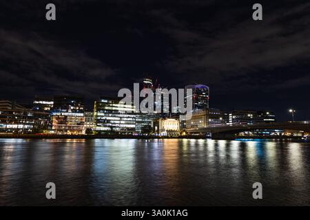 Vue imprenable sur Londres la nuit avec gratte-ciel illuminés et reflets sur la Tamise Banque D'Images