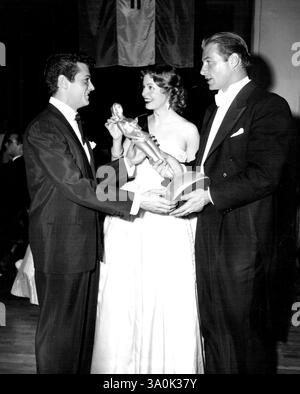Autorisation accordée pour la reproduction de journaux et de magazines. Tony Curtis, la jeune étoile montante d'Universal-International, reçoit une statuette présentée par Arlene Dahl et Lex Barker au nom de l'association de presse étrangère d'Hollywood qui a honoré Curtis comme l'un des six nouveaux arrivants à l'écran « dont les réalisations les ont marqués pour la célébrité internationale dans un avenir proche ». 16 avril 1952. (Photo par Universal - International). Banque D'Images