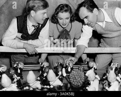 Une Symphonie en miniature..... Professeur Henry Rox, professeur adjoint d'art au Mt. Holyoke College, Mass., a conçu cet orchestre de figures d'art périssable pour une utilisation dans un numéro musical de nouveauté dans 'Strike Up the Band' de Metro-Goldwyn-Mayer. La figure de Bach est faite d'argile avec des têtes faites de divers fruits. De nombreux instruments sont également construits, et chaque figure est faite pour se déplacer en rythme avec la musique, actionnée par des leviers sous la table. Le réalisateur Busby Berkeley et Mickey Rooney et Judy Garland, co-stars du film, inspectent le décor unique. 10 janvier 1940. (Photo de Metro-Goldwyn-Maye Banque D'Images