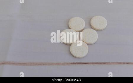 5 pilules beiges rondes sur une table blanche, photographie à plat, macro-plan, gros plan. Banque D'Images