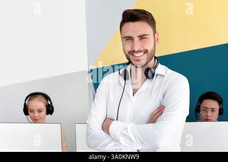 Portrait d'un représentant positif du service clientèle et de ses collègues au centre d'appels contemporain Banque D'Images