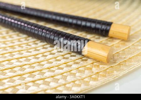 Vue détaillée des baguettes traditionnelles en bambou sur la surface du tapis tissé Banque D'Images