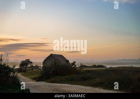 Village de pêcheurs historique avec de vieilles cabanes en bois de roseau pendant le coucher du soleil sur un étang Banque D'Images