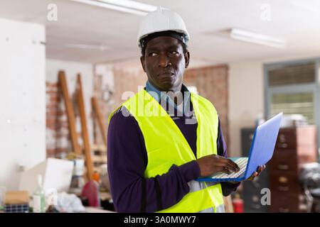 Ingénieur afro-américain avec ordinateur portable dans la construction ubder Banque D'Images