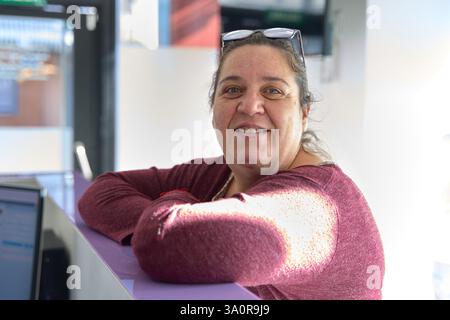Portrait d'une dentiste confiante souriante, appuyée sur le bureau d'accueil de sa clinique dentaire moderne Banque D'Images