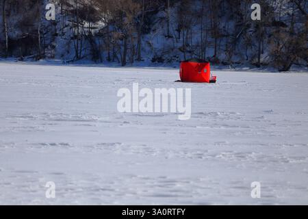 Tentes de pêche sur glace installées sur une baie gelée au cœur de l'hiver Banque D'Images