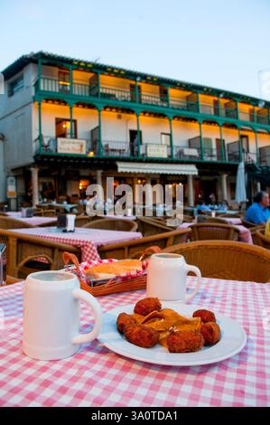 Croquettes et deux cruches de lager dans une terrasse, vue nuit. Main Square, Chinchon, Province de Madrid, Espagne. Banque D'Images