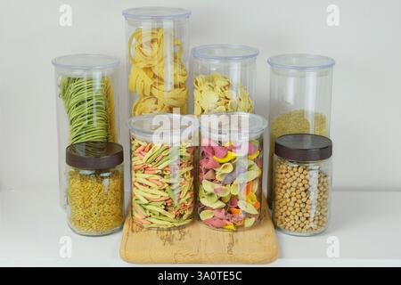 Variété de pâtes multicolores et autres produits d'épicerie dans des récipients en verre. Types de pâtes non cuites, pois chiches, riz et boulgour. Stockage d'un foo différent Banque D'Images