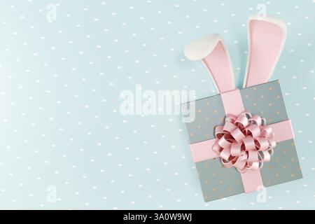 Boîte cadeau de Pâques avec oreilles de lapin et un noeud décoratif sur fond bleu clair. rendu 3d. Banque D'Images