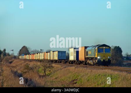 Une locomotive diesel de classe 66 numéro 66561 passe les signaux du sémaphore à Manea tout en travaillant sur un service freightliner le 24 février 2025. Banque D'Images