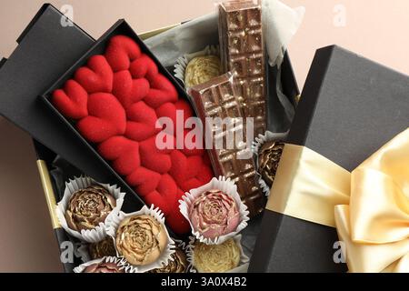 Différents délicieux bonbons au chocolat dans la boîte sur fond beige, vue de dessus Banque D'Images