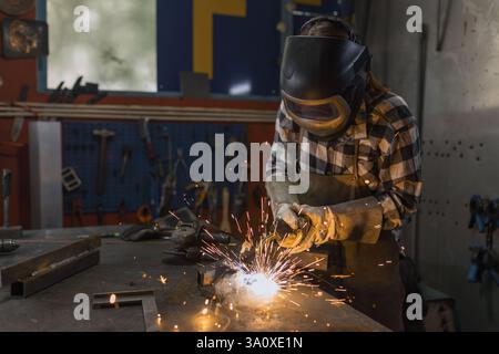 Habile et dévoué soudeur femelle soudeur en acier dans un atelier à la maison sombre. Concept de démarrage de petite entreprise. Banque D'Images
