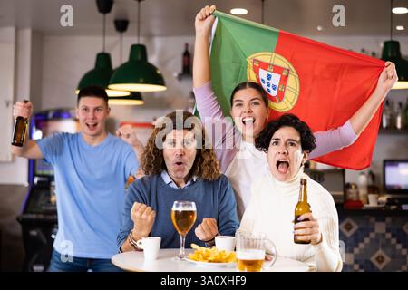 Les fans du drapeau du Portugal célèbrent la victoire de leur équipe préférée au bar à bière Banque D'Images