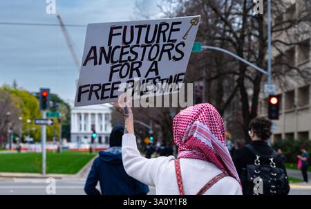 Sacramento, CA U.S.A. - 4 mars 2025 : une femme dans un keffiyeh tient un signe pro-palestinien alors qu'elle se dirige vers le Capitole à la démocratie du 4 mars 50501 Banque D'Images