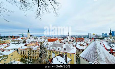 Vue aérienne pittoresque des toits de tuiles rouges enneigés des maisons dans le centre historique de Tallinn par une journée nuageuse Banque D'Images