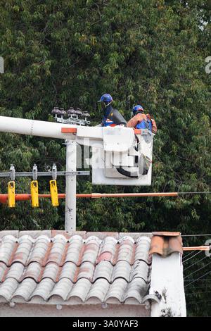 BOGOTA, COLOMBIE - 05 MARS 2025 deux travailleurs de la société ENEL effectuant des travaux d'entretien électrique au sommet d'un poteau lumineux Banque D'Images
