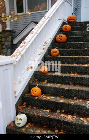 Citrouilles d'Halloween sculptées reposant sur les marches avant d'une maison Banque D'Images