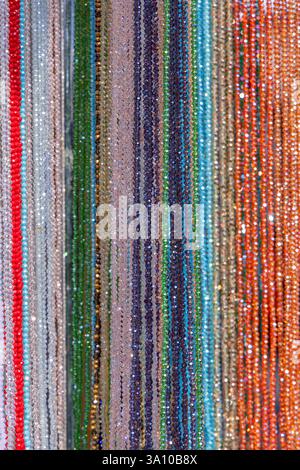 Fond de brins de perles multicolores disposés en rangées verticales des surfaces chatoyantes réfléchissent la lumière Banque D'Images