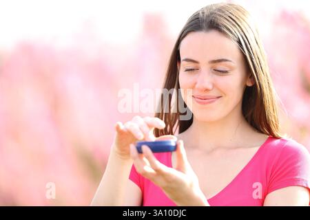 Femme satisfaite appliquant la crème hydratante de pot dans la nature Banque D'Images