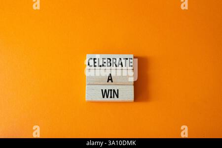 Célébrez un symbole gagnant. Les mots conceptuels célèbrent une victoire sur des blocs de bois. Beau fond orange. Et célébrez un concept gagnant. Copier l'espace. Banque D'Images