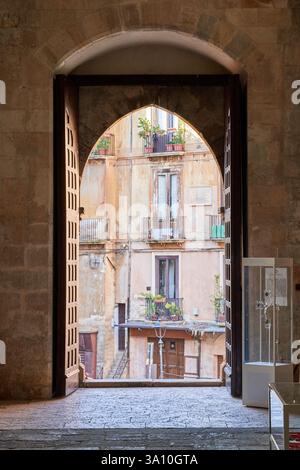 Vue à travers la porte voûtée en pierre de la cathédrale de Cosenza en regardant vers les bâtiments historiques de la place, Cosenza, Calabre, Italie. Banque D'Images
