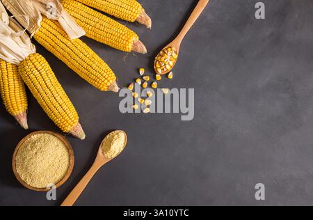 Farine de maïs dans un bol en bois et cuillère avec des gruaux de maïs séchés, des amandes sur une table rustique. Concept des ingrédients de maïs Banque D'Images