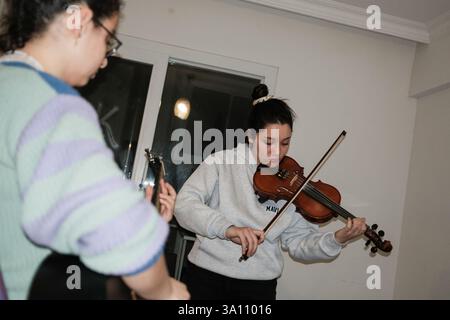 Izmir, Turquie. 05 mars 2025. Les femmes jouent de la guitare et du violon. Des femmes féministes ont organisé un atelier de bannières quelques jours avant le 8 mars, Journée internationale de la femme. Le 8 mars, ils préparent des banderoles pour la Marche nocturne féministe. Crédit : SOPA images Limited/Alamy Live News Banque D'Images