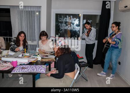 Izmir, Turquie. 05 mars 2025. Les femmes font de la musique tout en préparant des bannières. Des femmes féministes ont organisé un atelier de bannières quelques jours avant le 8 mars, Journée internationale de la femme. Le 8 mars, ils préparent des banderoles pour la Marche nocturne féministe. (Photo de Murat Kocabas/SOPA images/Sipa USA) crédit : Sipa USA/Alamy Live News Banque D'Images