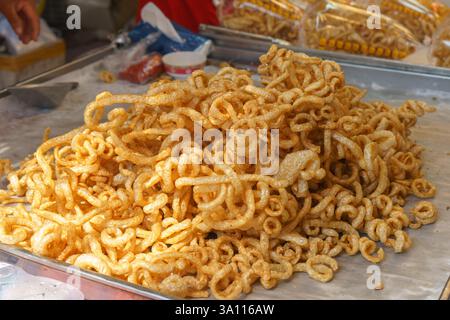 Gros plan de croûtes de porc bouclées, connues localement sous le nom de Kaep Moo, frites à un brun doré et exposées sur un stand de restauration de rue. Banque D'Images
