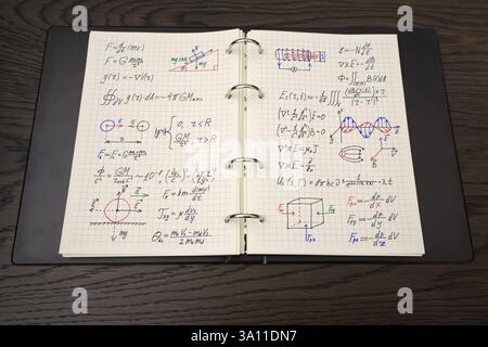 Un carnet ouvert révèle des équations mathématiques complexes et des graphiques colorés, accompagnés d'un luxueux stylo doré Banque D'Images