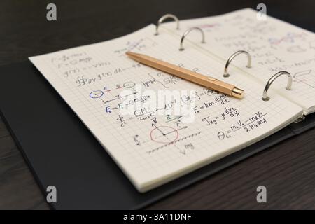 Un carnet ouvert révèle des équations mathématiques complexes et des graphiques colorés, accompagnés d'un luxueux stylo doré Banque D'Images