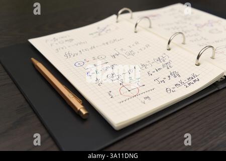 Un carnet ouvert révèle des équations mathématiques complexes et des graphiques colorés, accompagnés d'un luxueux stylo doré Banque D'Images