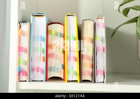 Livres avec des onglets colorés sur étagère blanche à l'intérieur Banque D'Images