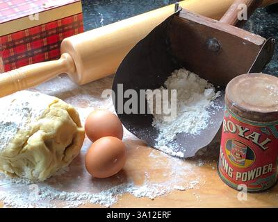 Cette installation de cuisson rustique comprend de la pâte maison, des œufs, de la farine et un rouleau à pâtisserie en bois. Amateurs de pâtisserie à la recherche d'une scène de cuisine de ferme. Banque D'Images