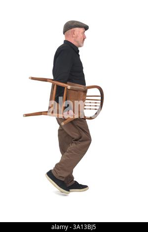 vue latérale d'un homme marchant portant chaise vintage sur fond blanc Banque D'Images
