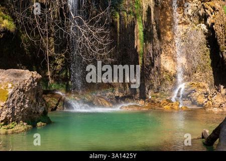 Les cascades d'eau descendent une falaise rocheuse, créant une cascade étonnante qui se jette dans une piscine turquoise limpide. Une végétation luxuriante entoure la région, mettant en valeur t Banque D'Images