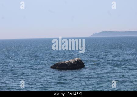 Une formation rocheuse étonnante émergeant de la mer cristalline sous le soleil d'été brillant. Banque D'Images