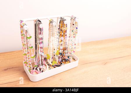 Chaînes colorées faites à la main de perles, perles et pierres naturelles suspendues sur un support blanc. Placer pour le texte. Banque D'Images
