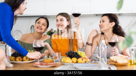Des femmes heureuses se sont rassemblées autour d'une table festive ; participant à des discussions animées et appréciant les délices du vin Banque D'Images