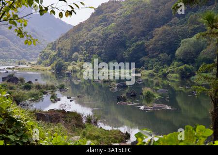 Comté d'Imsil, Corée du Sud - 4 octobre 2021 : une section tranquille de la rivière Seomjin coule à travers des collines luxuriantes et boisées, avec des rochers dispersés qui se brisent Banque D'Images
