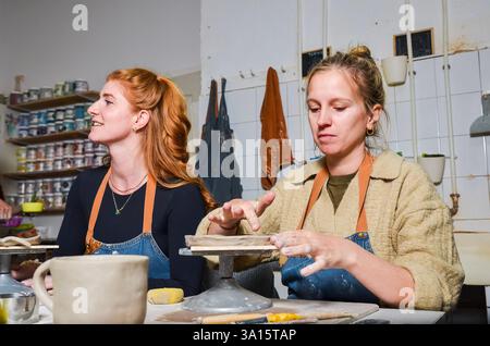 Deux artisans travaillant avec de l'argile dans un atelier de poterie, créant des céramiques artisanales Banque D'Images