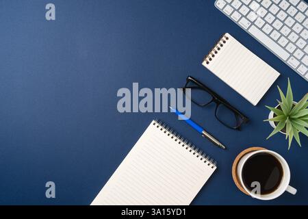 Vue de dessus d'un espace de travail moderne avec cahiers vierges, stylo, lunettes, café et clavier Banque D'Images