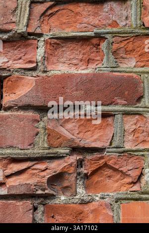 Gros plan d'un mur de briques avec quelques briques brisées et cassées, révélant des textures rugueuses, des fissures et des surfaces altérées. Idéal pour l'arrière-plan Banque D'Images